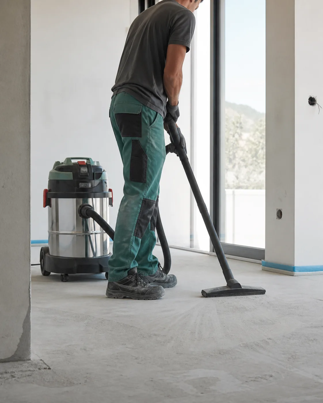 Profissional a aspirar o pavimento de um apartamento em fase de acabamento